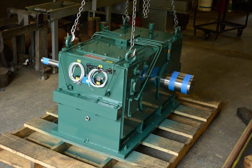 A finished green industrial gearbox on a pallet, ready to ship